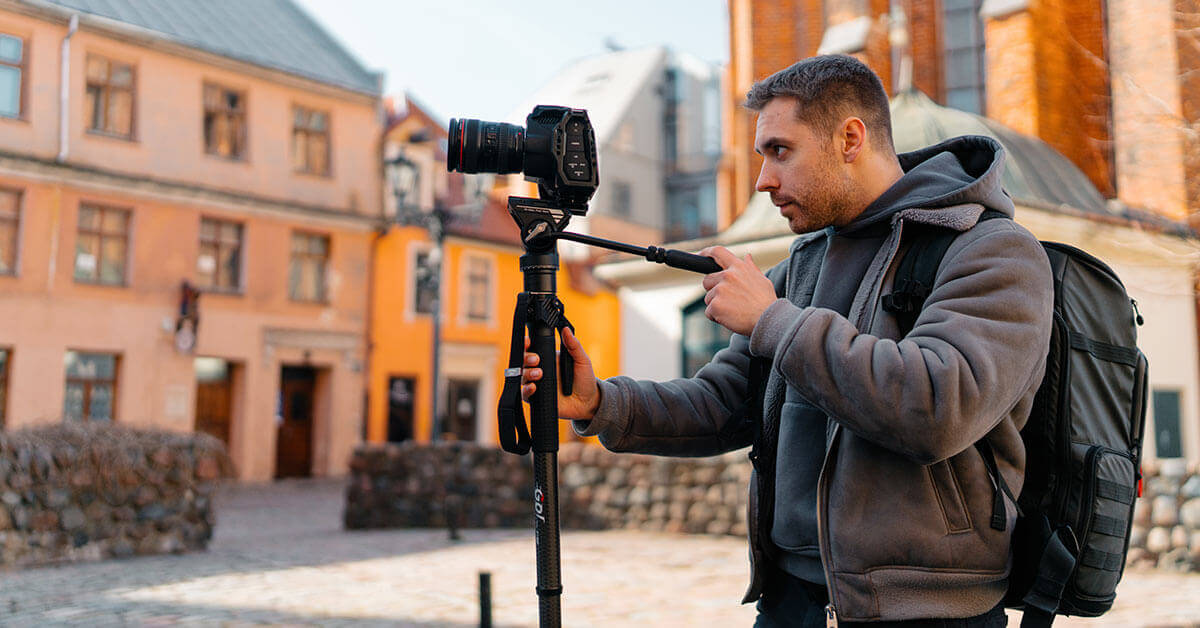 Man using a lightweight carbon fiber monopod to take photos in a historic urban setting.