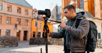 Man using a lightweight carbon fiber monopod to take photos in a historic urban setting.